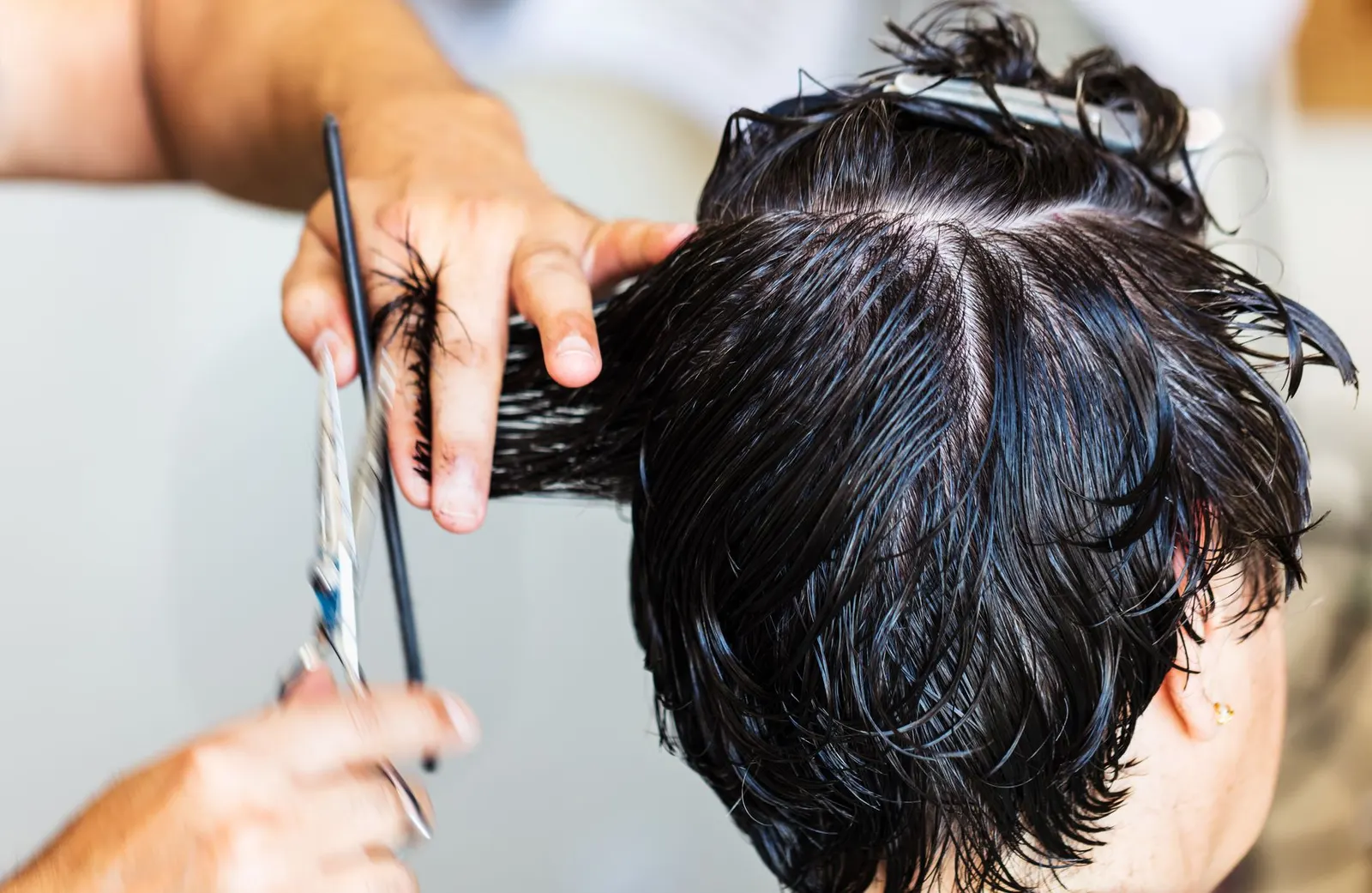 Coiffeuse en train de couper des cheveux mouilles en salon